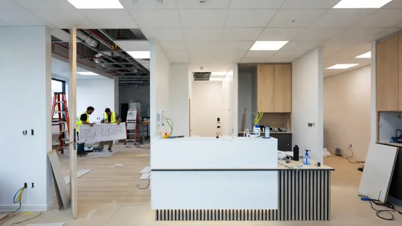 Modern medical clinic interior under construction in Melbourne, showing reception desk, consultation rooms, exposed ceiling services and builders reviewing plans during fit-out